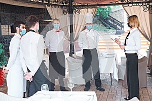 A team of waiters conduct a briefing on the summer terrace of the restaurant