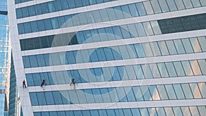 Team of washers cleaning modern office building skyscraper windows