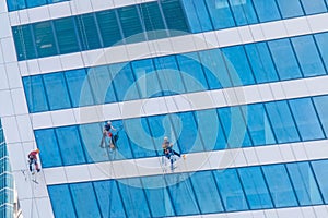 Team of washers cleaning modern office building skyscraper windows