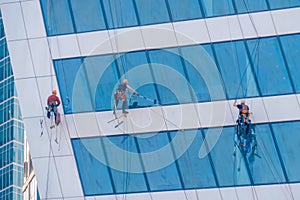 Team of washers cleaning modern office building skyscraper windows