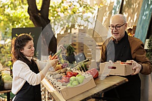 Team of woman and elderly man vendors selling healthy farm produce