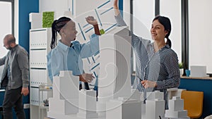 Team of women giving highfive after architecture work progress with building model