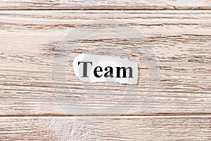 TEAM of the word on paper. concept. Words of TEAM on a wooden background