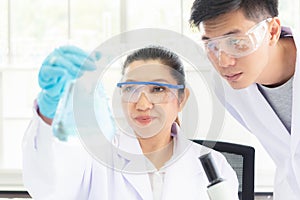 Team work asian woman and man Scientists analyzing study data and evaluating microscope