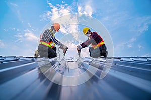 Team work construction worker safety wear using electric drill tools install on new roof metal sheet, Roof construction concept