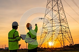 Team work of Engineers location help Technician use drone to fly inspections at the electric power station to view the planning