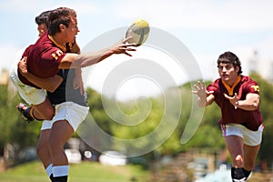 Team work is important to win. a young rugby player executing a pass mid-tackle.