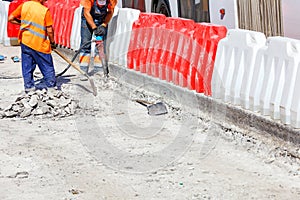 A team of workers cleans some of the concrete with a jackhammer during road construction