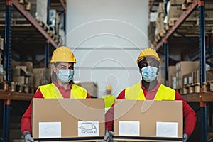 Team working in warehouse loading delivery boxes while wearing face surgical mask during corona virus pandemic