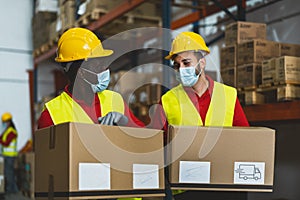 Team working in warehouse loading delivery boxes while wearing face surgical mask during corona virus pandemic