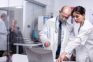 Team of young doctors pointing on laptop anlysing result of patient