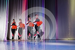 team of young girls - athletes are preparing for the show, many young cheerleaders are standing on stage behind the curtain