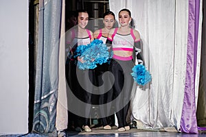 Team of young girls - athletes are preparing for the show, many young cheerleaders are standing on stage behind the curtain, sport