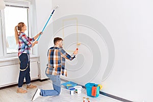 Team of young painters in checkered wear with rollers working indoors