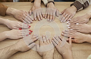 Team of young people having a meeting and holding their hands together on the table