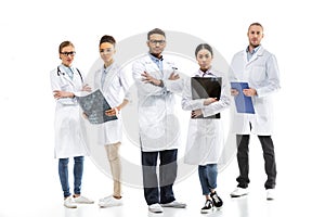 Team of young professional doctors in white coats standing together