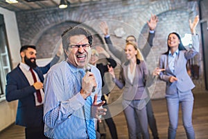 Teambuilding indoors activity. Business people making team training exercise during team building seminar singing karaoke