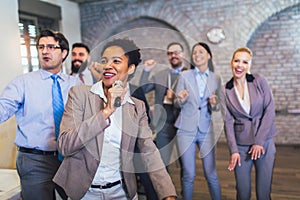 Teambuilding indoors activity. Business people making team training exercise during team building seminar singing karaoke