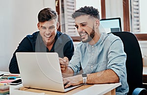 Teamed up to take on any business challenge. two young businessmen using a laptop together in a modern office.