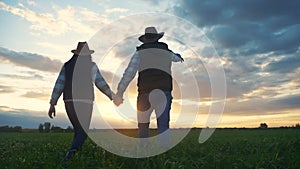 Teamwork. Agriculture harvesting concept. Happy farmers family group of people hold hands walking across the field at