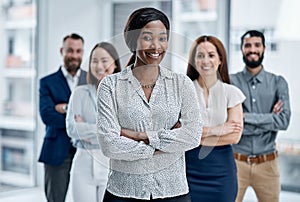 Teamwork is a big benefit to us all. Portrait of a businesswoman standing in an office with her colleagues in the