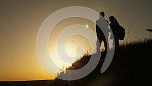 Teamwork of business people. traveler man extends his hand to a girl climbing to the top of a hill. travelers climb the