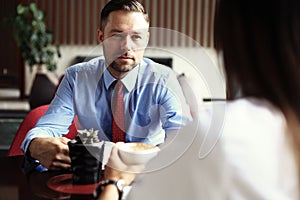 Teamwork. Businessman and businesswoman sitting at table in coffee shop and discuss business plan. On table is laptop