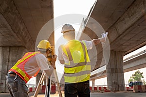 Teamwork of civil engineer and surveyor engineers making measuring under the expressway with theodolite on road works. Survey