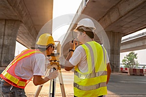 Teamwork of civil engineer and surveyor engineers use radio communication and making measuring with theodolite on road works.