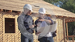Teamwork. concept building constructing architect slow motion video. two men builder in helmets study digital tablet the