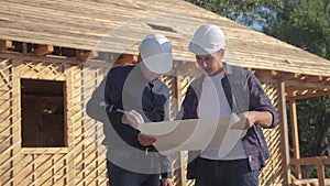 Teamwork. concept building constructing architect slow motion video. two men builder in helmets study the house plan