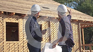 Teamwork. Concept building constructing architect slow motion video. Two men builder in helmets study the house plan
