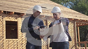 Teamwork. concept building constructing architect slow motion video. Two men builder in helmets study the house plan