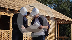 Teamwork. concept building constructing architect slow motion video. two men builder in helmets study the house plan