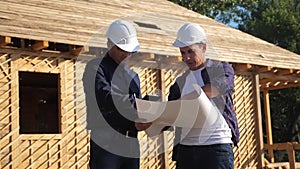 Teamwork. concept building constructing architect slow motion video. Two men builder in helmets study the house plan