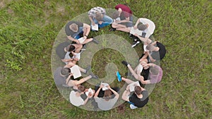 Teamwork concept. A group of high school students sit on the grass in a circle. Drone view.