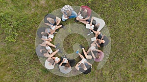 Teamwork concept. A group of high school students sit on the grass in a circle and scatter in different directions