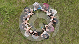 Teamwork concept. A group of high school students sit on the grass in a circle and scatter in different directions