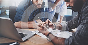 Teamwork concept.Group of three coworkers working together in modern coworking studio.Bearded man using smartphone