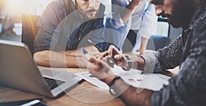 Teamwork concept.Group of three coworkers working together in modern coworking studio.Bearded man using smartphone and