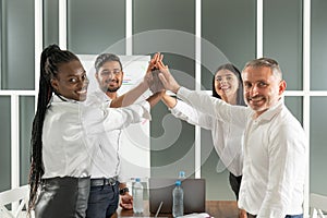 Teamwork concept. Happy successful multiracial business team giving a high fives gesture as they laugh and cheer their