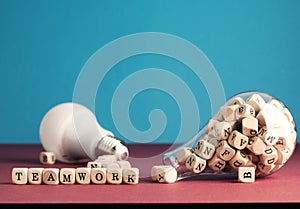 Teamwork concept with a lot of alphabetically labeled wooden blocks in a light bulb