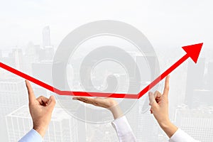 Teamwork concept suggested by three business peopleâ€™s hands guiding an arrow graph chart to go upwards