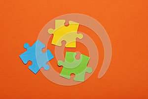 Teamwork concept - Three puzzle pieces of blue, green and yellow color on orange background