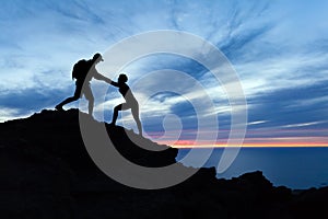 Teamwork couple hikers silhouette in mountains, climbers team