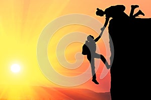 Teamwork couple hiking help each other trust assistance silhouette in mountains, sunset. Teamwork of man and woman hiker helping e