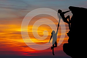 Teamwork couple hiking help each other trust assistance silhouette in mountains, sunset. Teamwork of man and woman hiker helping e