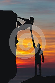 Teamwork couple hiking help each other trust assistance silhouette in mountains, sunset. Teamwork of man and woman hiker helping e