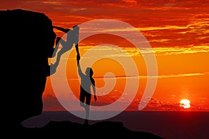 Teamwork couple hiking help each other trust assistance silhouette in mountains, sunset. Teamwork of man and woman hiker helping e