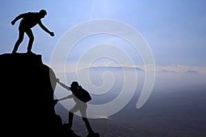 Teamwork couple hiking help each other trust assistance silhouette in mountains, sunset. Teamwork of man and woman hiker helping e